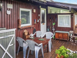 A wooden deck with a table and chairs, a door, and a window.