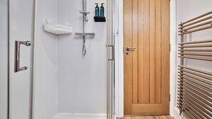 Ein Badezimmer mit Dusche, einer Holztür und einem Handtuchhalter.