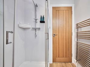 Ein Badezimmer mit Dusche, einer Holztür und einem Handtuchhalter.