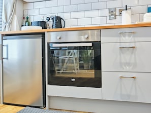 Eine kleine Küche mit Kühlschrank, Backofen und weißen Schränken.