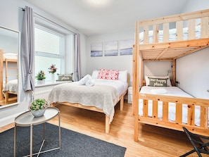 A room with a bunk bed, a desk, a chair, a small table with a plant, and a window with curtains. - No.1 Princess Yellow Apartments - UK52052 (Portrush)