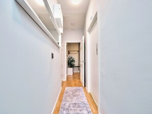 A hallway with white walls, a wooden floor, and a patterned rug. - No.2 Princess Yellow Apartments - UK52053 (Portrush)