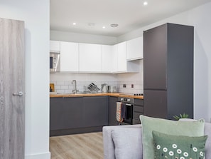 A modern kitchen with white cabinets, a grey countertop, and a built-in oven. - Green Mill 3-UK52057 (Holmfirth)