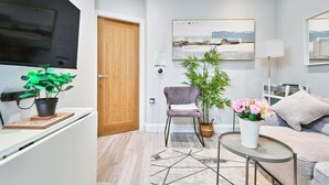Un salon moderne avec un canapé, une table basse, un fauteuil, une lampe et un grand tableau accroché au mur.
