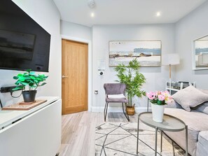 A modern living room with a sofa, a coffee table, a chair, a lamp, and a large painting on the wall. - No.3 Princess Yellow Apartments - UK52054 (Portrush)