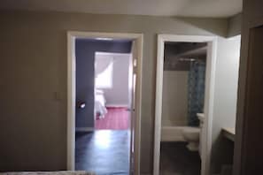 Ein Flur, der zu einem Badezimmer mit Toilette und Dusche führt.