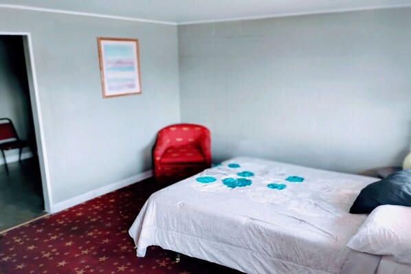 Una habitación con una cama, una silla roja, un cuadro enmarcado en la pared y una alfombra estampada con estrellas.