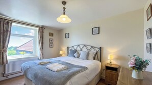 Quarto bem arrumado com cama, abajures, janela com cortinas e vista para o exterior.
