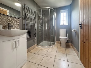 Ein Badezimmer mit Duschkabine aus Glas, Toilette, Waschbecken mit Spiegel und Fenster.