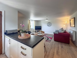 Ein kompakter Wohnbereich mit Küchenzeile, Essplatz und einem roten Sofa.