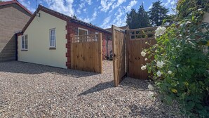Una proprietà residenziale con vialetto sterrato, cancello in legno e muro di mattoni.