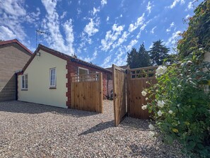 Ein Wohnhaus mit Kiesweg, Holztor und Backsteinmauer.