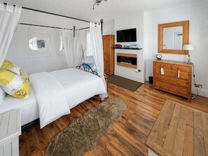 A bedroom with a bed, a wooden dresser, a TV mounted on the wall, and a mirror above the dresser. - 3 bedroom accommodation in Sandilands (Sandilands)