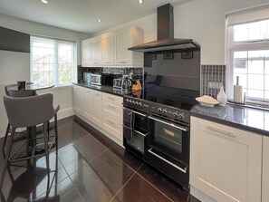 A modern kitchen with white cabinetry, a black stove, and a large window. - 3 bedroom accommodation in Sandilands (Sandilands)