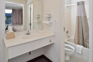 Ein Badezimmer mit Waschbecken, Spiegel, Handtuchhalter, Toilette und Badewanne.