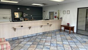 A reception area with a counter, a clock, a plant, and a small table. - King Bed Smoking|Budget Inn Greenville (Greenville SC)