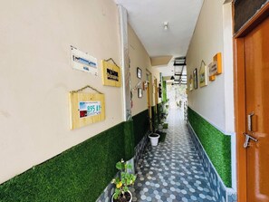 A hallway with green and white walls, a tiled floor, and various signs and decorations. - Paradise Inn Dharmsala (Dharamshala)