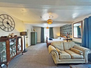 A room with a bed, a vintage armchair, a wooden cabinet, and a large wall clock. - Period-style studio apartment in Hereford with a gentle, vintage charm. (Hereford)