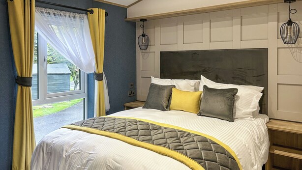 Ein Schlafzimmer mit Bett, Vorhängen, Kopfteil und Fenster.