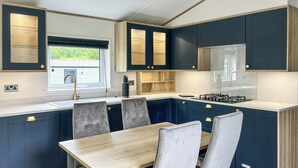Eine moderne Küche mit dunkelblauen Schränken, einem Holztisch und grau gepolsterten Stühlen.