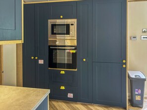 Una cocina con microondas, horno y armarios.