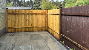 Eine Terrasse mit Steinplatten und einem Holzzaun.