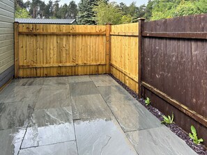 A patio with stone tiles and a wooden fence.