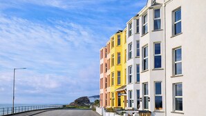 A coastal street with colorful buildings, a clear sky, and a view of the sea. - Glan Y Mor - UK52092 (Criccieth)