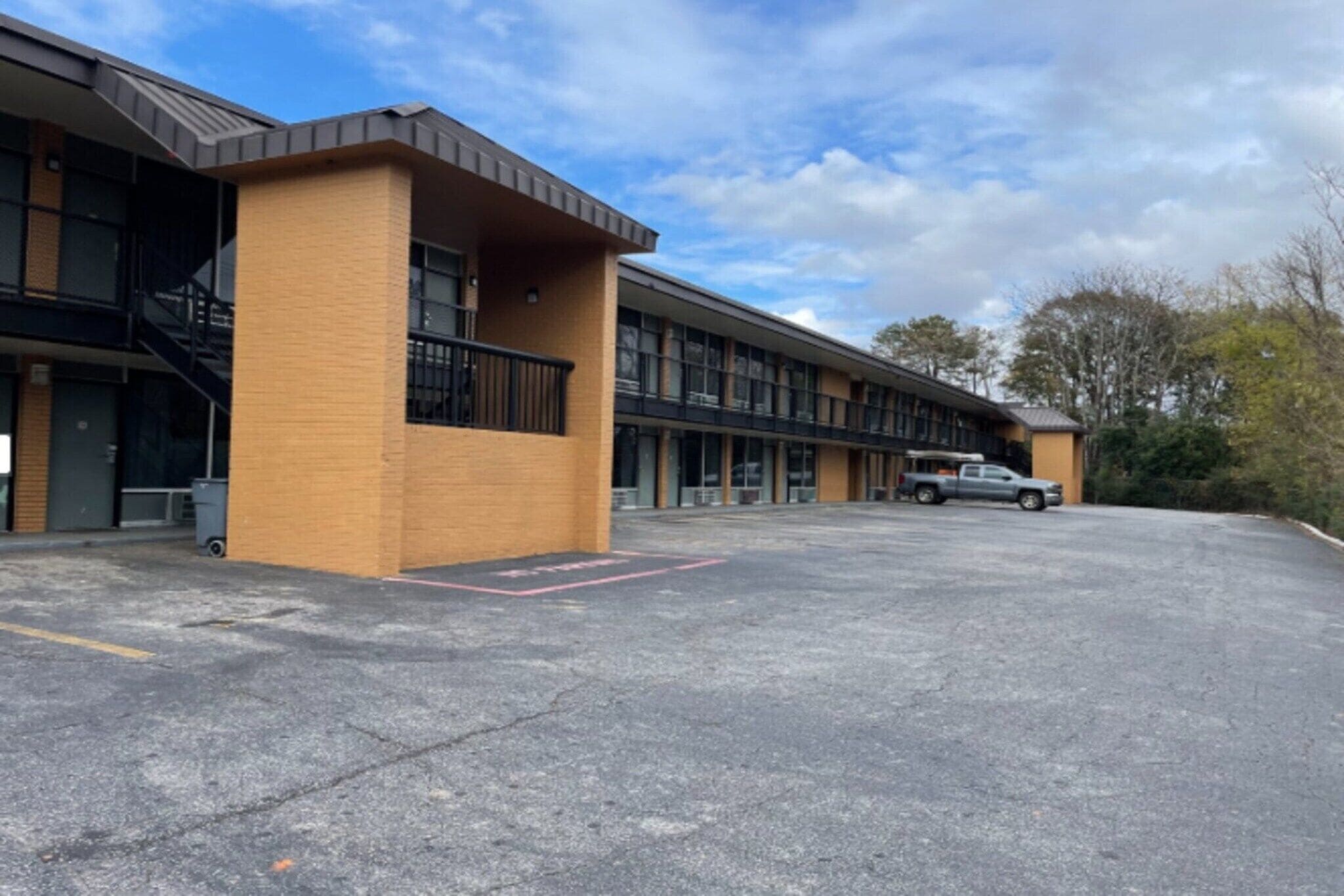 A building with a parking lot, a staircase, and a vehicle.