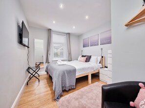 A bedroom with a bed, a TV mounted on the wall, a desk, and a window with curtains. - No.4 Princess Yellow Apartments - UK52100 (Portrush)
