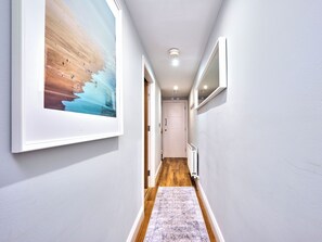 A hallway with a framed picture, a radiator, and an exit door. - No.4 Princess Yellow Apartments - UK52100 (Portrush)