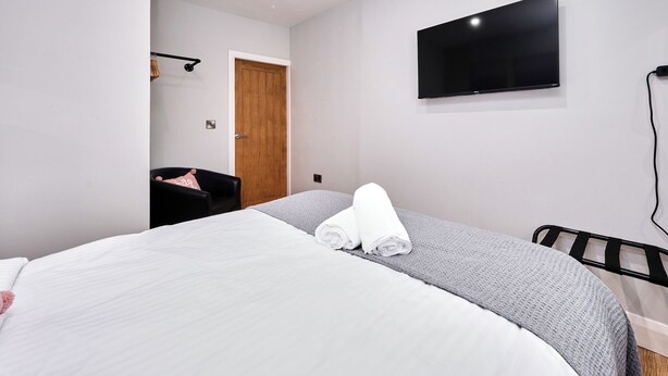 Una camera da letto con un letto, una TV a schermo piatto, una porta in legno e una sedia.
