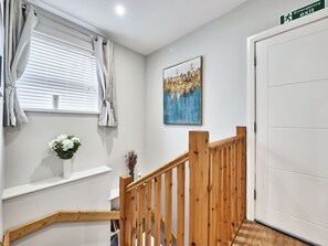 A staircase with wooden railings, a white door, and a wall-mounted emergency exit sign. - No.4 Princess Yellow Apartments - UK52100 (Portrush)