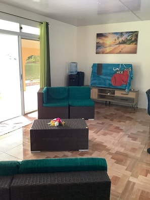 A living room with a sofa, a coffee table with flowers, a water dispenser, and a painting on the wall.