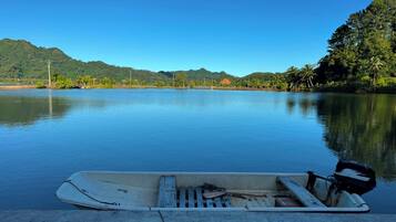 Un lago tranquilo con un bote amarrado en la orilla, rodeado de vegetación y colinas.