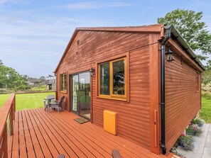 Eine Holzhütte mit einer Veranda, großen Fenstern und einer Tür zu einem Innenbereich.