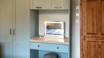 A room with a light blue desk, a mirror, a stool, and a wardrobe.