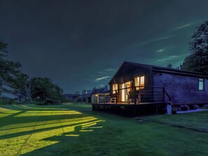 A house with a porch and a deck, surrounded by a grassy yard. - 1 bedroom accommodation in Brora (Brora)
