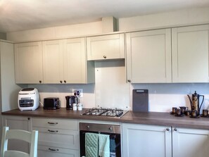 A kitchen with white cabinets, a toaster, a kettle, and a stove. - 1 bedroom accommodation in Brora (Brora)