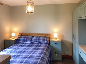 A bedroom with a bed, two bedside tables with lamps, a wardrobe, and a hanging light fixture. - 1 bedroom accommodation in Brora (Brora)
