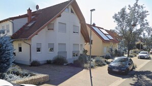 En bostadsgata med hus, en parkerad bil och en gatlykta.