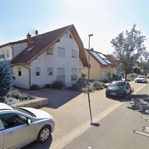 Une rue résidentielle bordée de maisons, avec une voiture garée et un lampadaire.