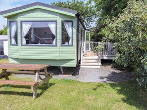 A green mobile home with a porch, a picnic table, and a gravel pathway. - Sarnfaen Static - UK52097 (Tal-y-Bont, near Barmouth)