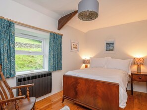 A bedroom with a bed, two bedside lamps, a radiator, a wooden chair, and a window with curtains. - 3 bedroom accommodation in Low Row, near Reeth (Low Row, near Reeth)