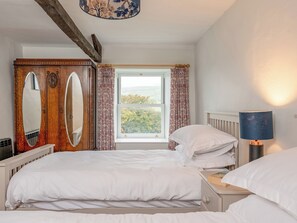A bedroom with two beds, a wooden wardrobe, a window with a view, and a bedside lamp. - 3 bedroom accommodation in Low Row, near Reeth (Low Row, near Reeth)