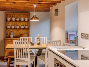 Ein Essbereich mit einem Holztisch, weißen Stühlen, einer Hängelampe, einer Weinflasche und einem Buch mit dem Titel 'Traditional Yorkshire Cooking'.
