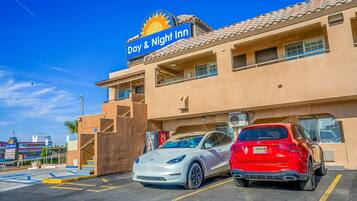 A Day & Night Inn with a parking lot, two parked cars, and a clear blue sky.