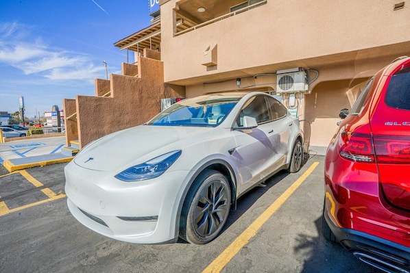 En vit Tesla står parkerad på en parkeringsplats med en byggnad i bakgrunden.