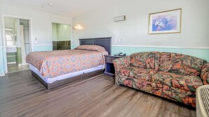 Een slaapkamer met een bed, een bank, een wandlamp en een lijst met een afbeelding.