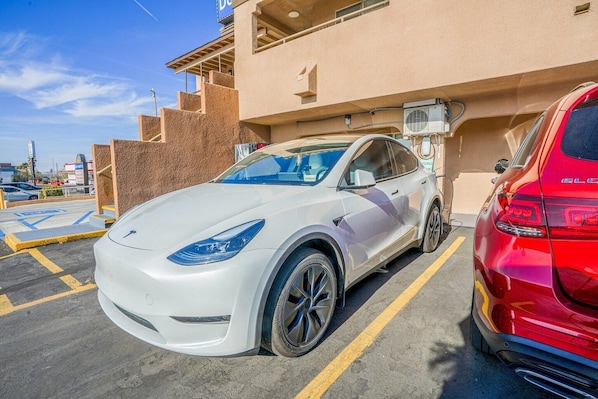 A parking lot with a white Tesla and a red SUV.